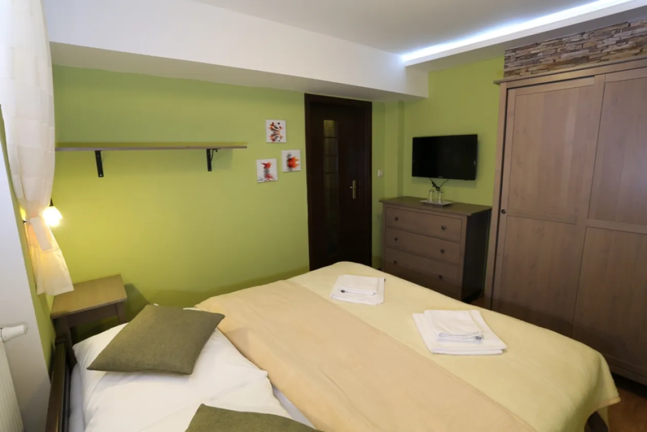 Izba v penzióne s dreveným obkladom a veľkoplošnou fotografiou Muránskej planiny nad posteľou